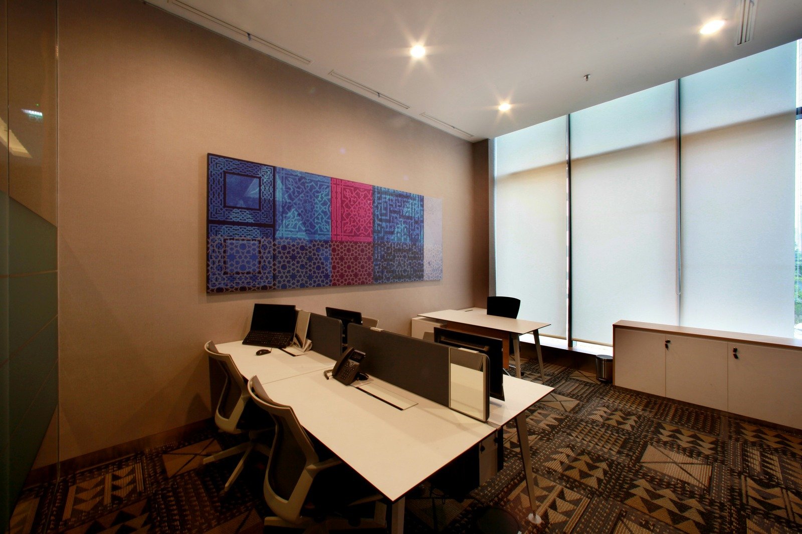 Modern private office suite with multiple desks, ergonomic chairs, and large windows.